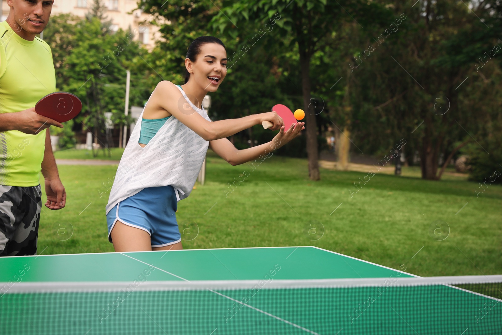 Photo of Friends playing ping pong outdoors on summer day