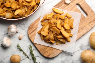 Photo of Delicious oven baked potatoes on marble table, flat lay