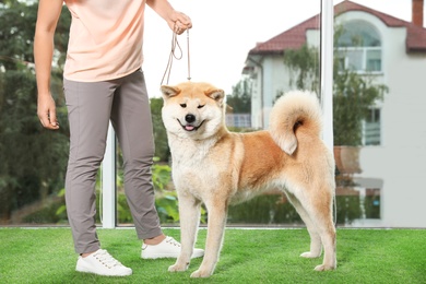 Photo of Young woman and adorable Akita Inu dog indoors. Champion training