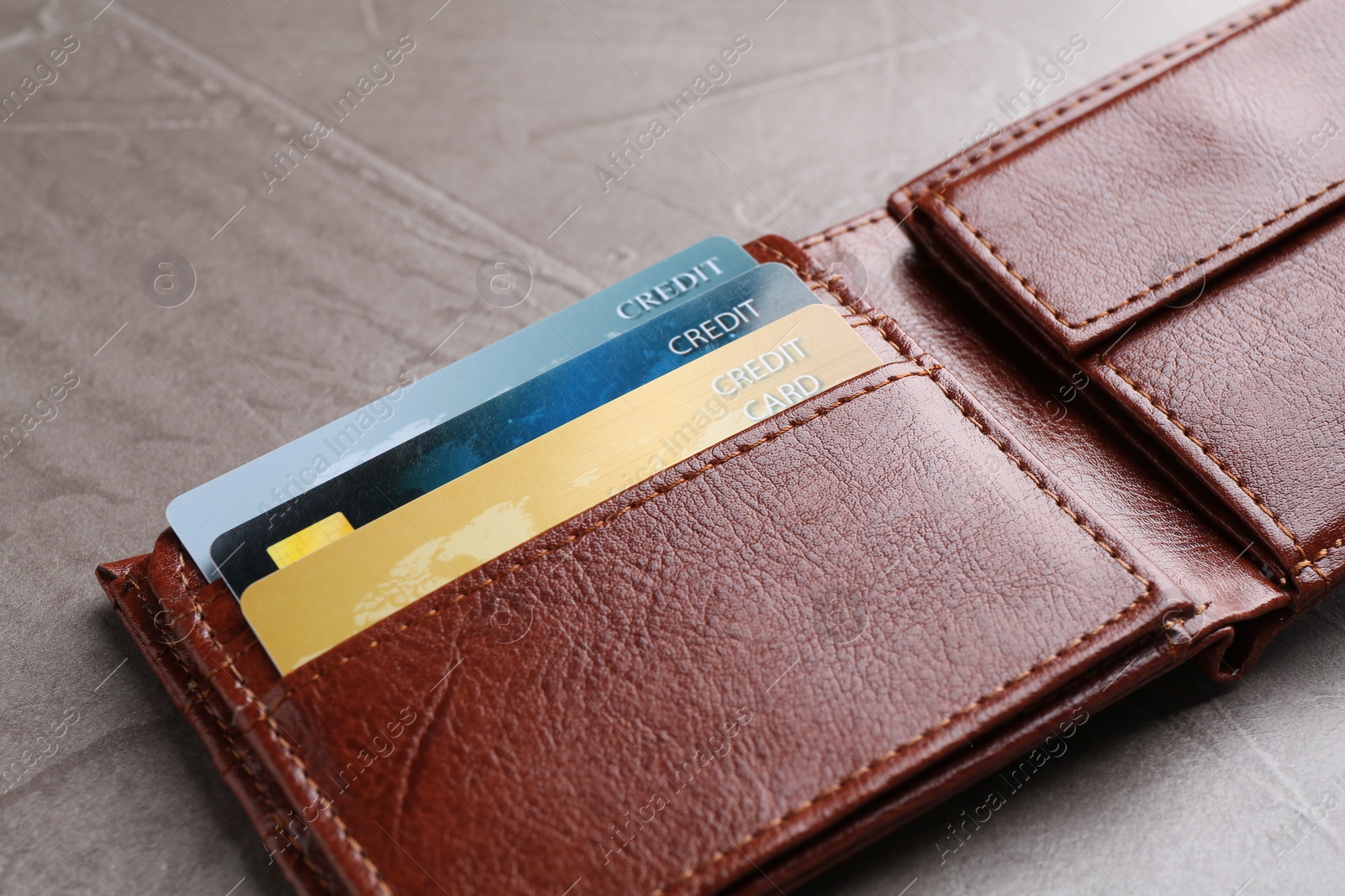 Photo of Credit cards in leather wallet on grey textured table, closeup