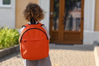 Little girl walking to kindergarten outdoors on sunny day, back view. Space for text