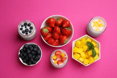 Photo of Jars of fresh yogurt and different fruits on pink background, flat lay