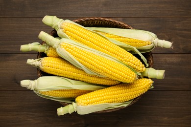 Tasty fresh corn cobs on wooden table, top view