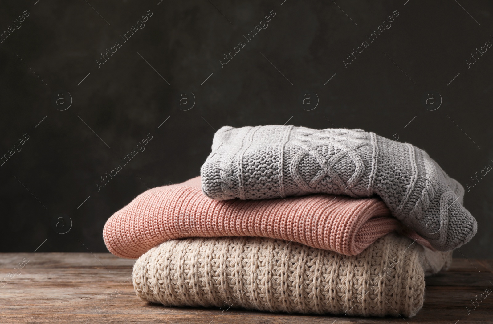 Photo of Stack of folded knitted sweaters on table. Space for text