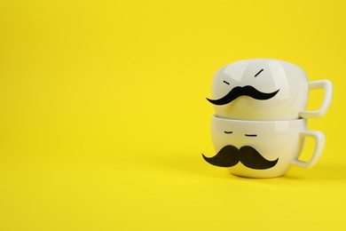 Photo of Men's faces made of cups, fake mustaches on yellow background. Space for text