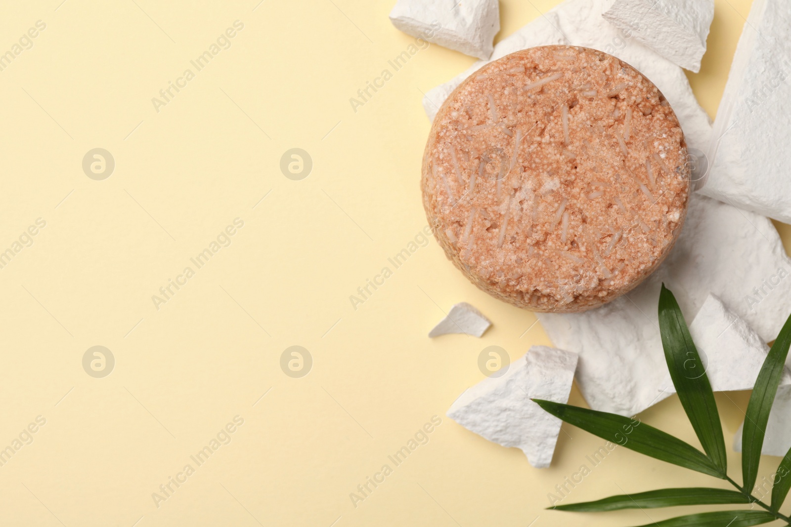 Photo of Flat lay composition of solid shampoo bar and leaf on beige background. Space for text