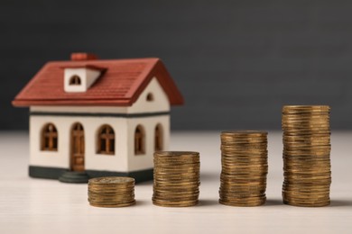 Photo of Mortgage. Stacked coins and house model on light table