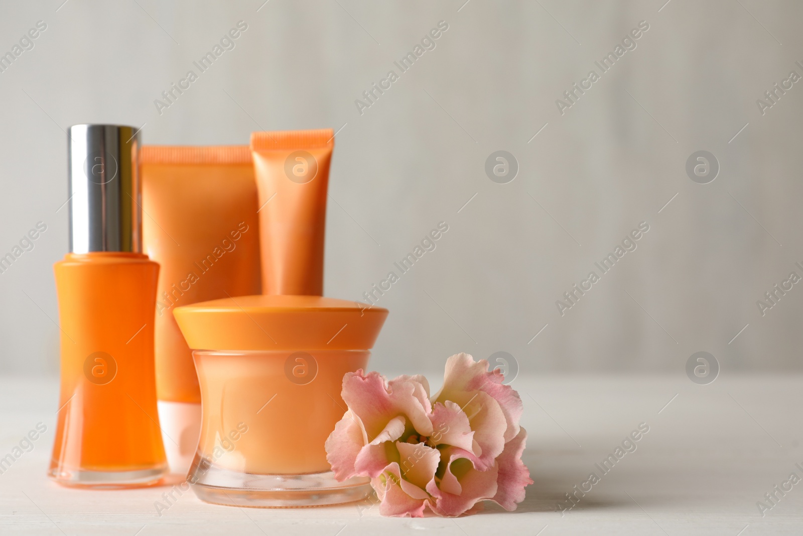 Photo of Set of luxury cosmetic products and beautiful flower on white table. Space for text