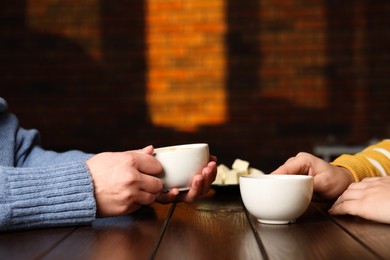 Photo of Women having coffee break at wooden table in cafe, closeup