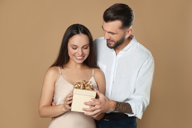 Photo of Lovely couple with gift on beige background