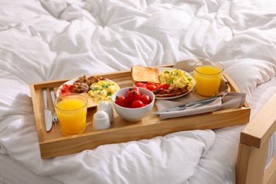 Photo of Good morning. Tray with tasty breakfast on bed