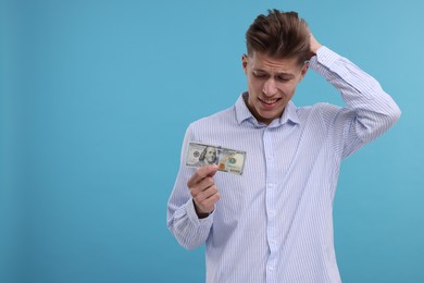 Photo of Upset man with dollar banknote on light blue background. Space for text