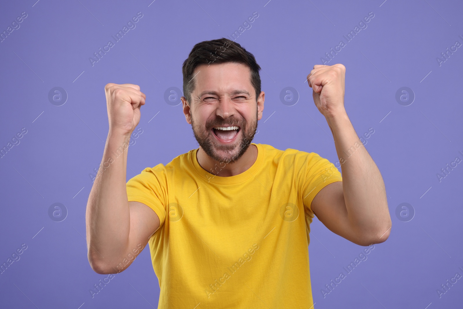 Photo of Emotional sports fan celebrating on purple background