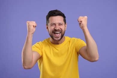 Emotional sports fan celebrating on purple background