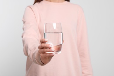 Photo of Healthy habit. Closeup of woman holding glass with fresh water on light grey background