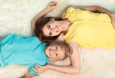 Mother and son lying on fuzzy rug, top view