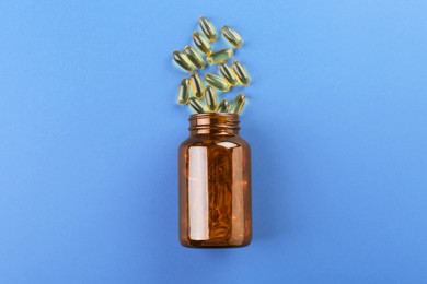 Photo of Jar with vitamin capsules on blue background, top view