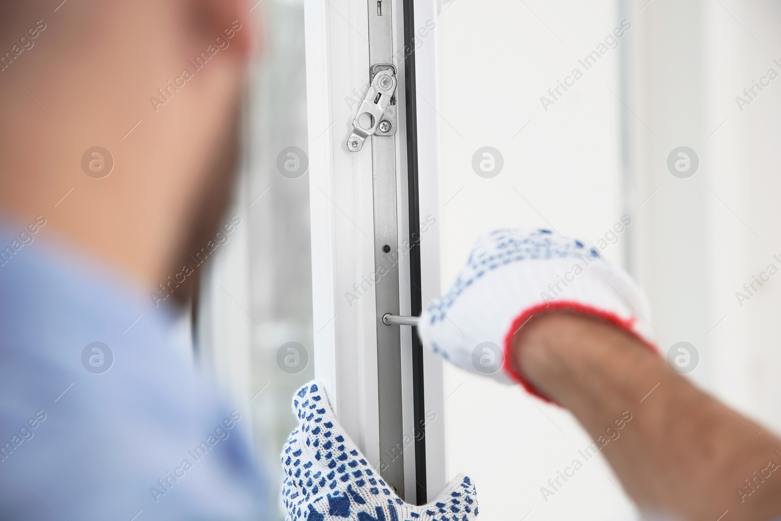 Photo of Construction worker adjusting installed window with screwdriver indoors, closeup