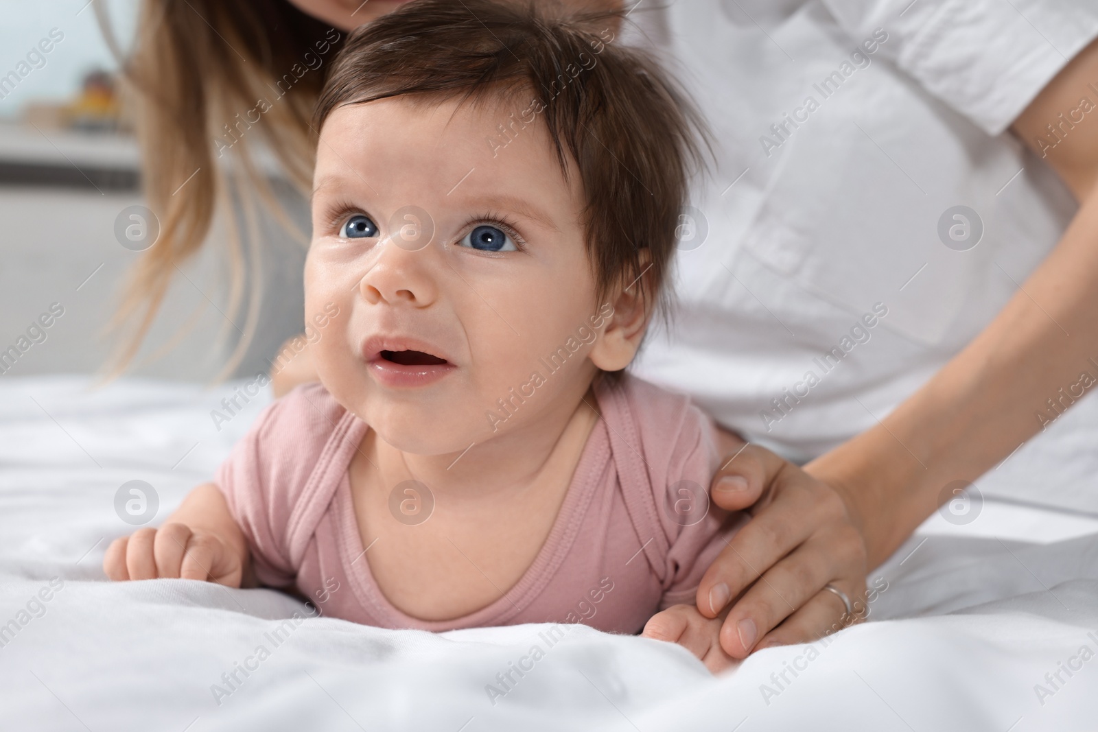 Photo of Little baby and mother on bed, closeup