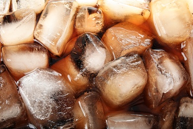 Closeup view of tasty refreshing cola with ice cubes as background