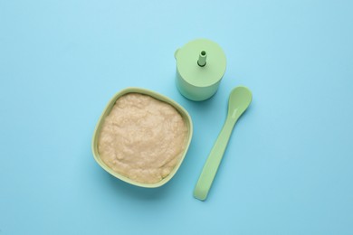 Photo of Healthy baby food in bowl and bottle with drink on light blue background, flat lay