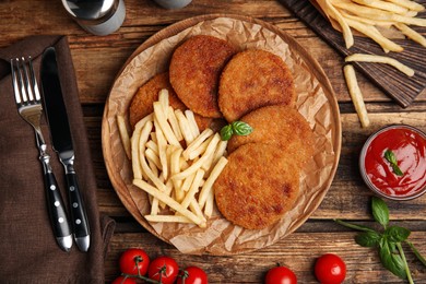 Delicious fried breaded cutlets served on wooden table, flat lay