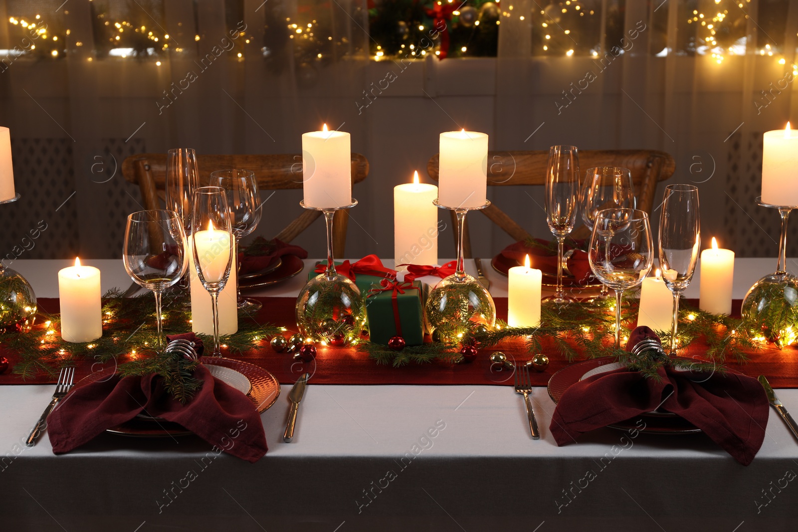 Photo of Christmas table setting with burning candles and festive decor