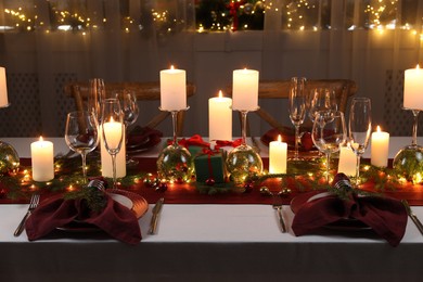 Photo of Christmas table setting with burning candles and festive decor