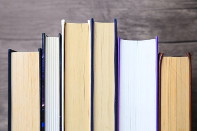 Photo of Collection of different books near wooden wall, closeup