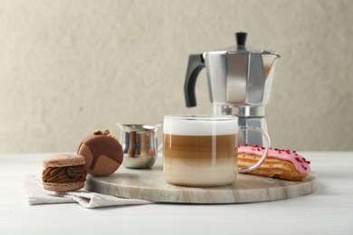 Photo of Aromatic coffee in cup, tasty macarons, eclair and moka pot on white wooden table