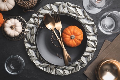 Photo of Autumn table setting with golden cutlery and pumpkins on black background, flat lay