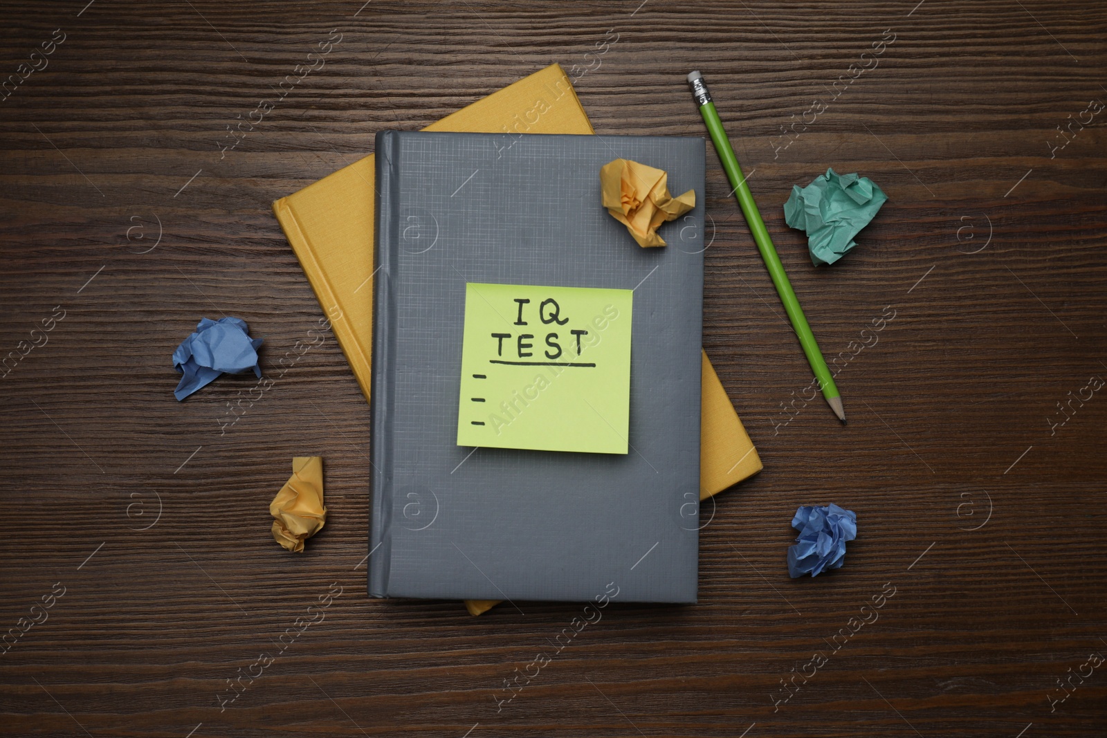 Photo of Sticky paper with words IQ Test, notebooks and pencil on wooden table, flat lay