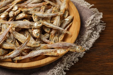 Tasty dried anchovies on wooden table, closeup