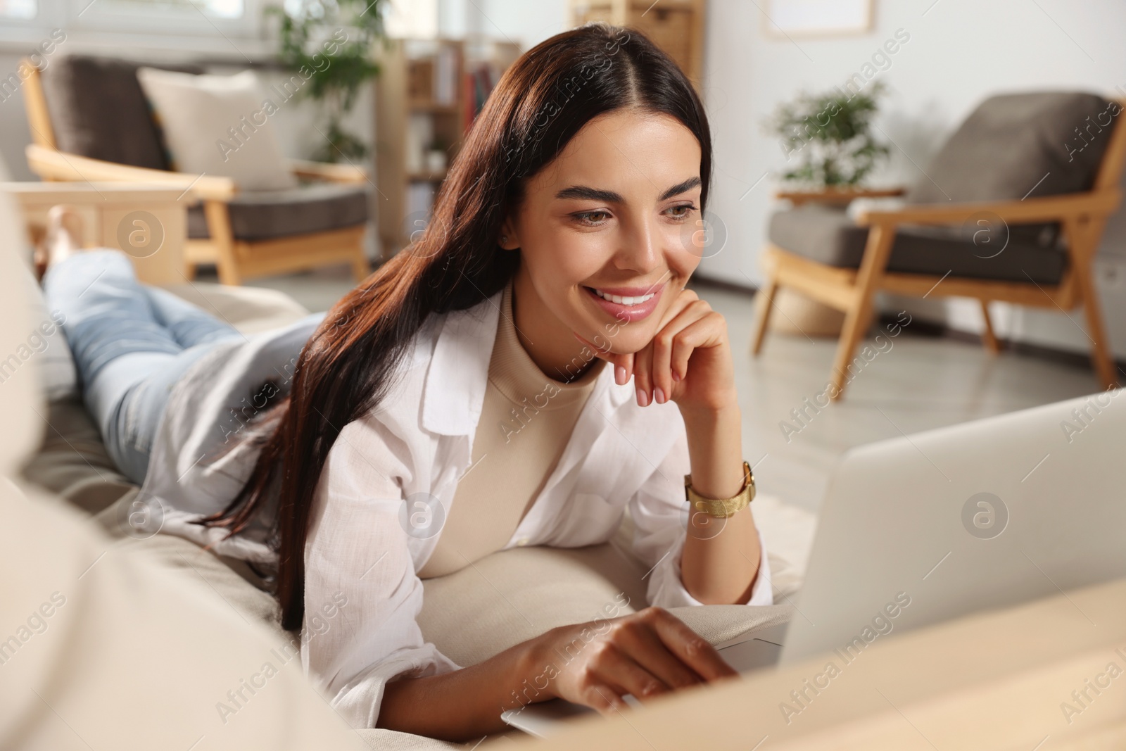 Photo of Young woman working with laptop on sofa at home