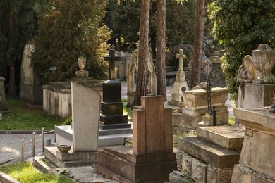 Photo of View of cemetery with granite tombstones on sunny day. Funeral ceremony