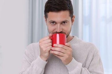 Photo of Man drinking from red mug at home