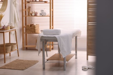 Photo of Comfortable massage table with clean towels in spa center