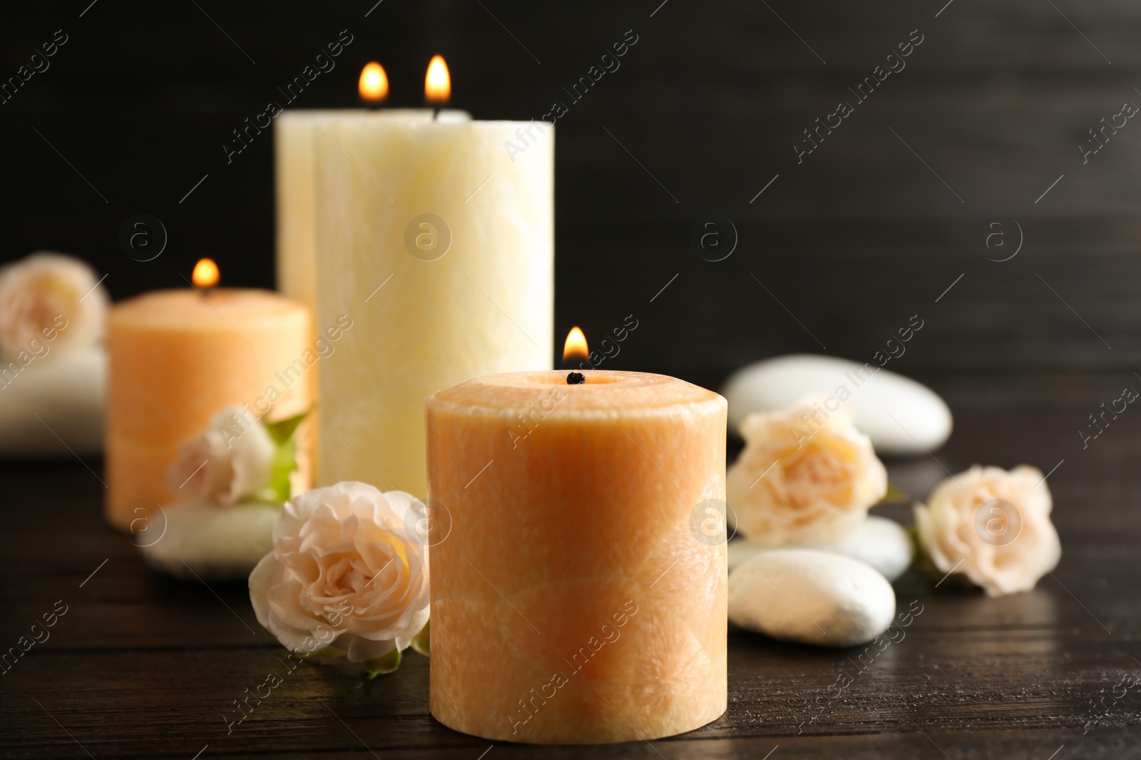 Photo of Burning candles, spa stones and flowers on table. Space for text