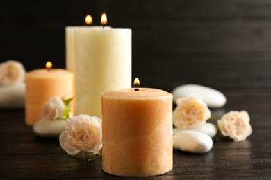 Photo of Burning candles, spa stones and flowers on table. Space for text