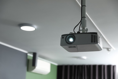 Photo of Modern video projector on ceiling in room
