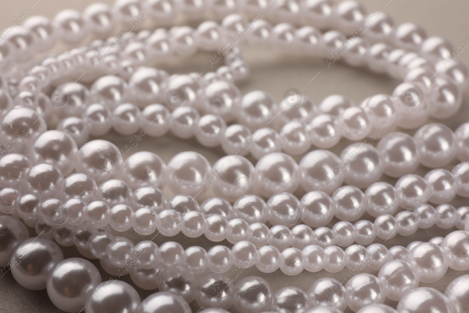 Photo of Elegant pearl necklace on beige background, closeup view