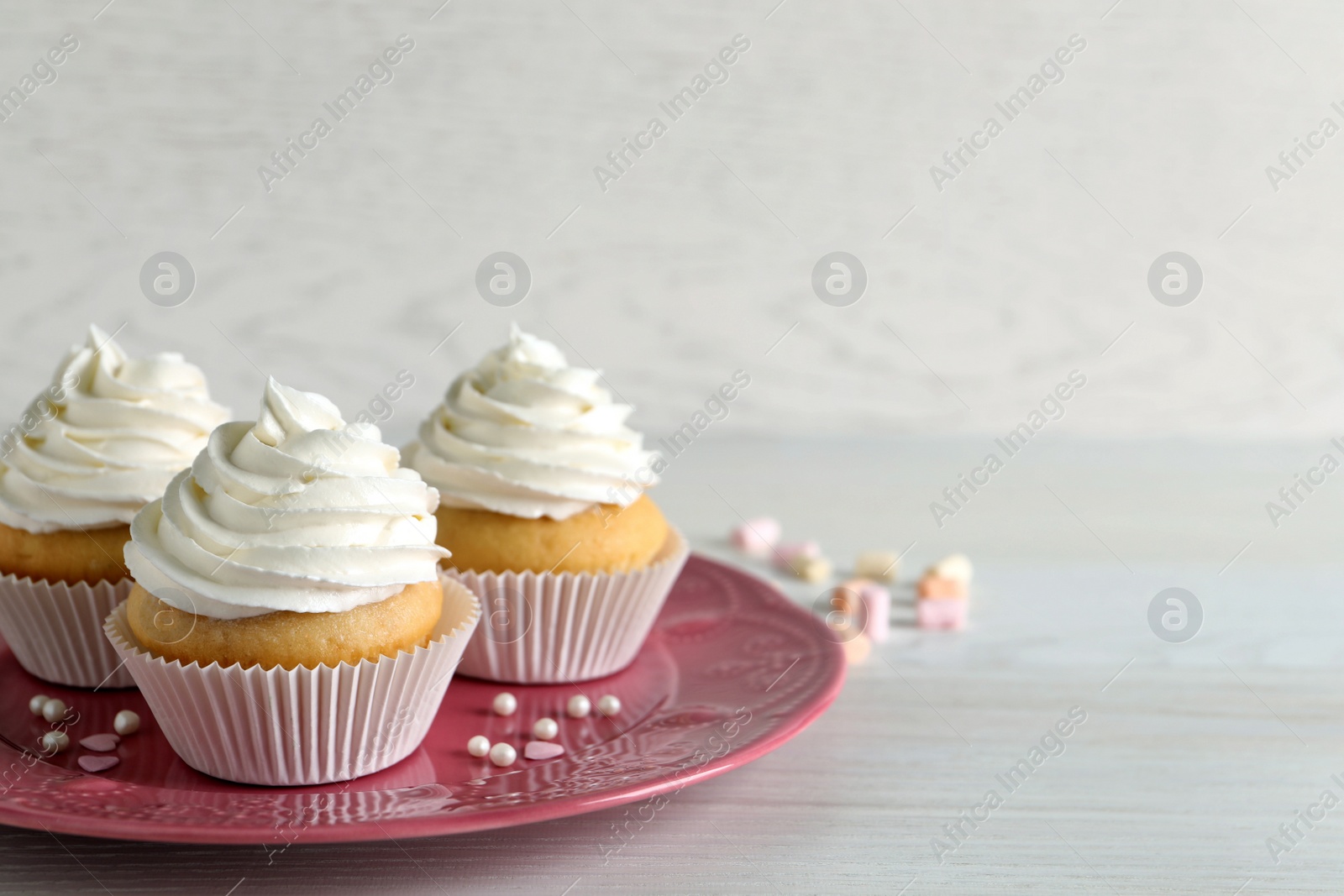 Photo of Delicious cupcakes with cream on white wooden table. Space for text