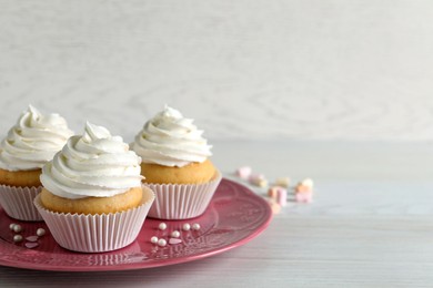 Photo of Delicious cupcakes with cream on white wooden table. Space for text
