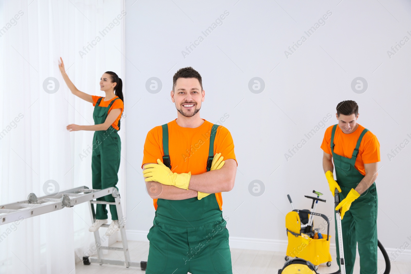 Photo of Team of professional janitors cleaning room after renovation