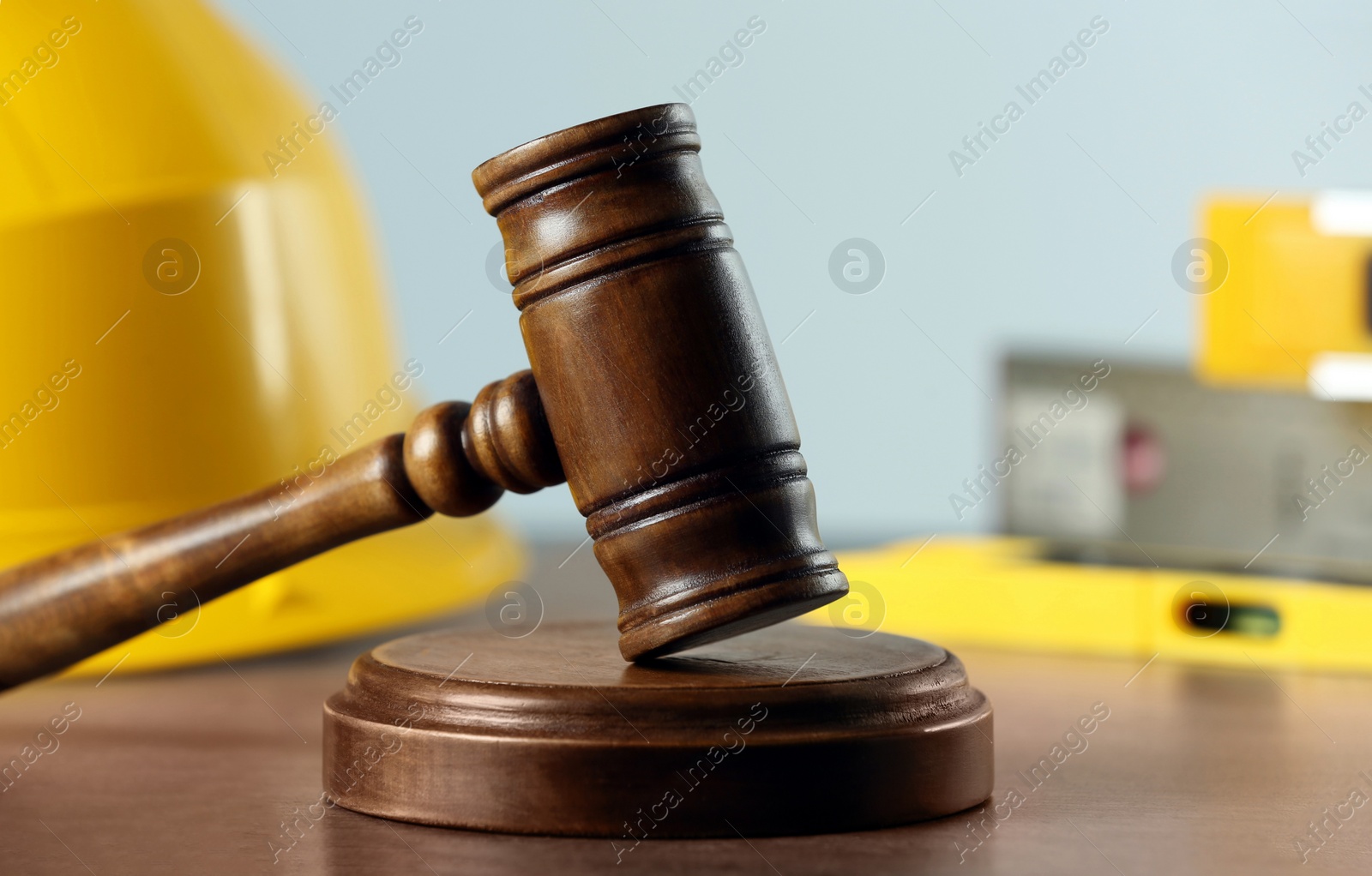 Photo of Construction and land law concepts. Judge gavel, protective helmet with levels on grey table