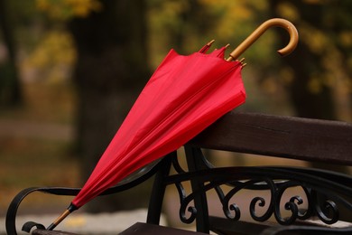Red umbrella on bench in autumn park