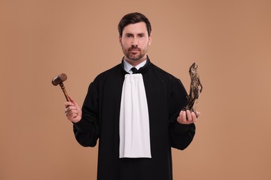 Photo of Judge with gavel and figure of Lady Justice on light brown background