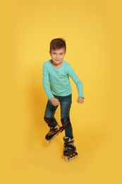 Photo of Little boy with inline roller skates on color background
