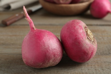 Photo of Ripe red turnips on wooden table, closeup