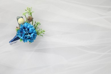 Photo of Wedding stuff. Stylish boutonniere on white veil, top view. Space for text